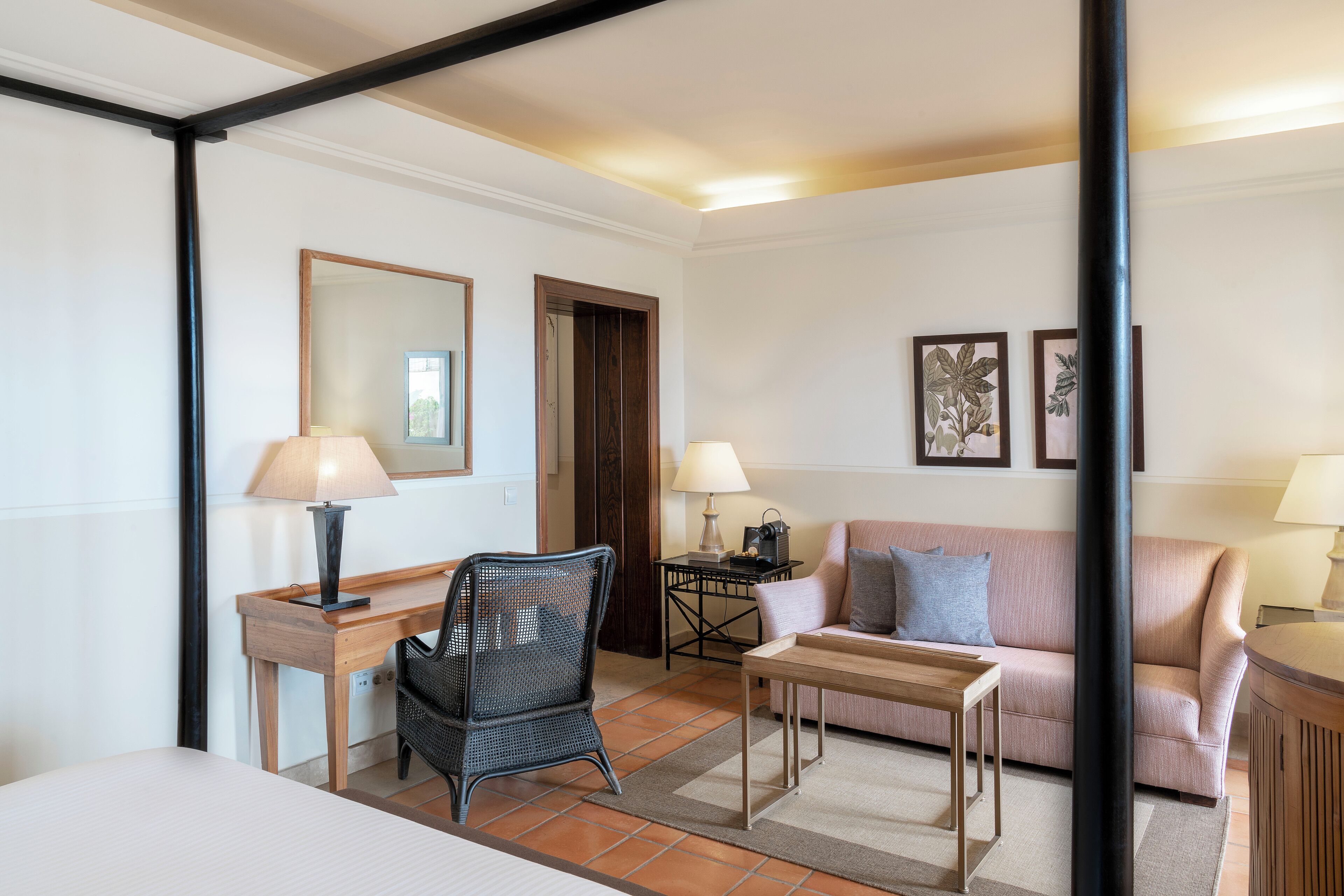 Una camera d'hotel con un letto, una scrivania, una sedia, un divano e due lampade.
