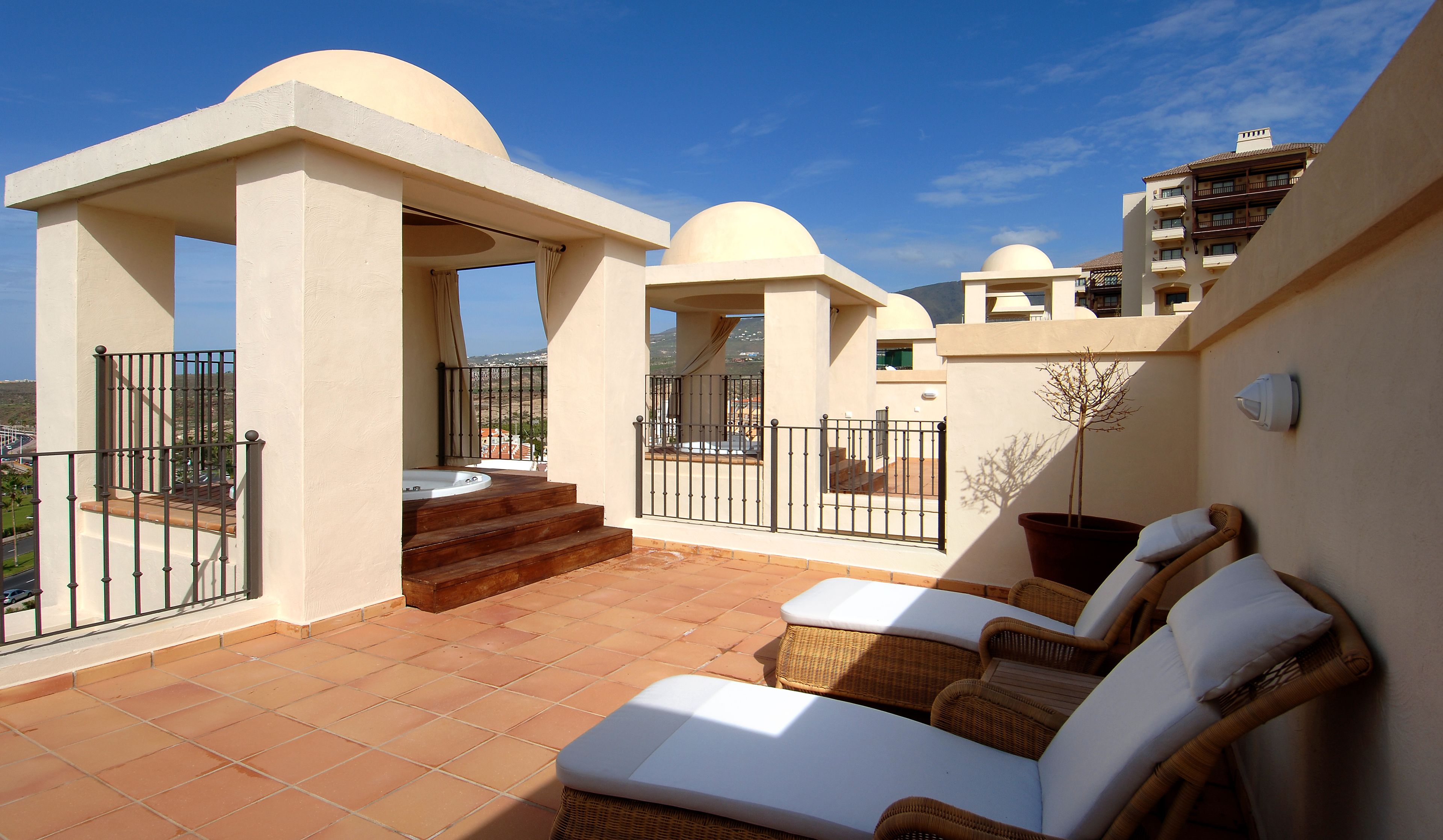 Una terraza en la azotea con jacuzzi, mobiliario exterior y vistas a la ciudad.