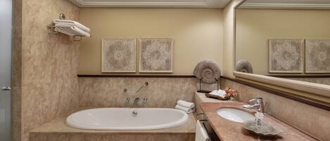 A modern bathroom with a large bathtub, two sinks, and decorative wall art.