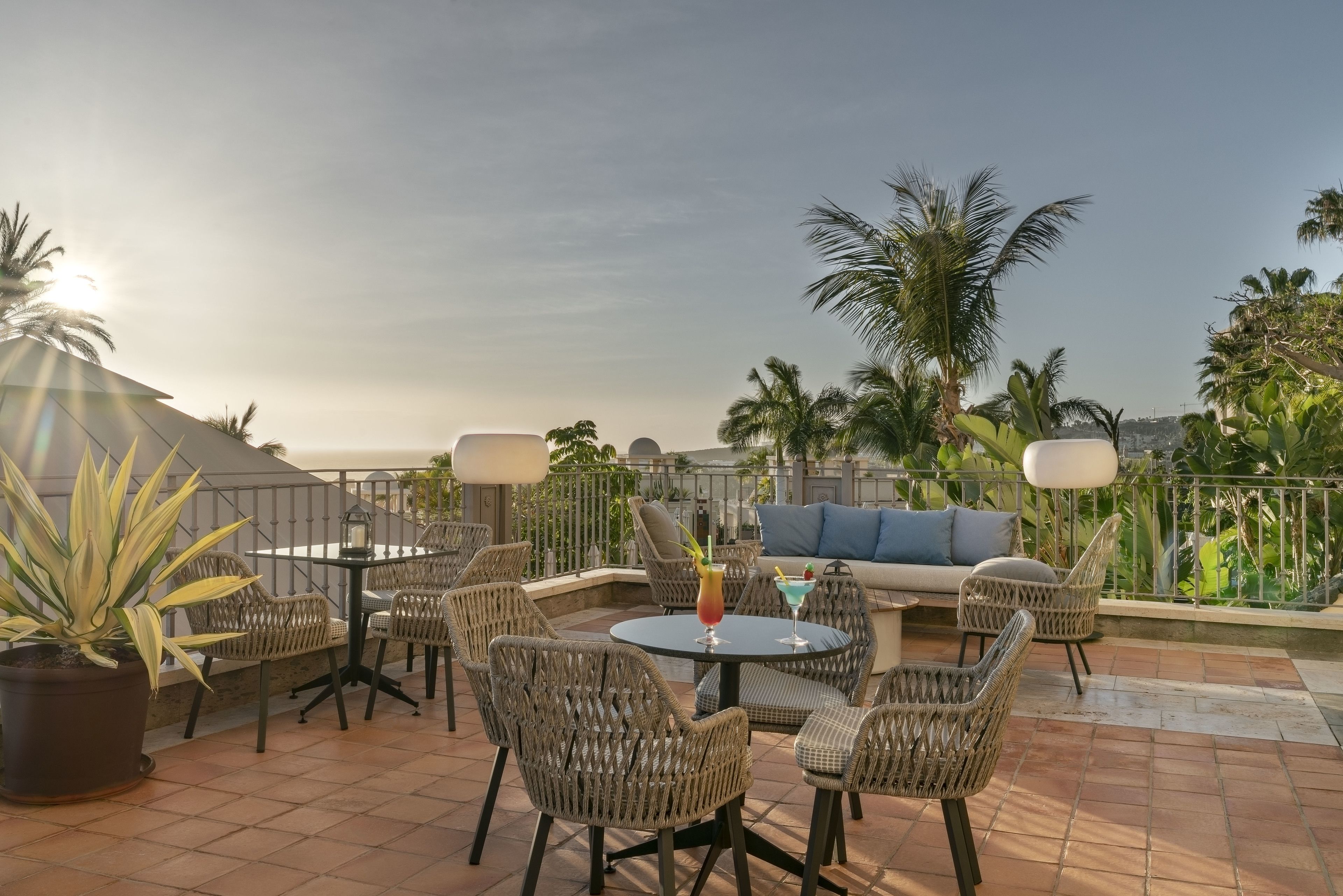 Un espace patio aménagé avec des meubles en osier, une table ronde et un canapé.