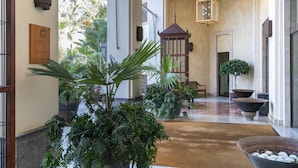 Un vestíbulo amplio con una columna central, plantas en macetas y un farol tradicional.