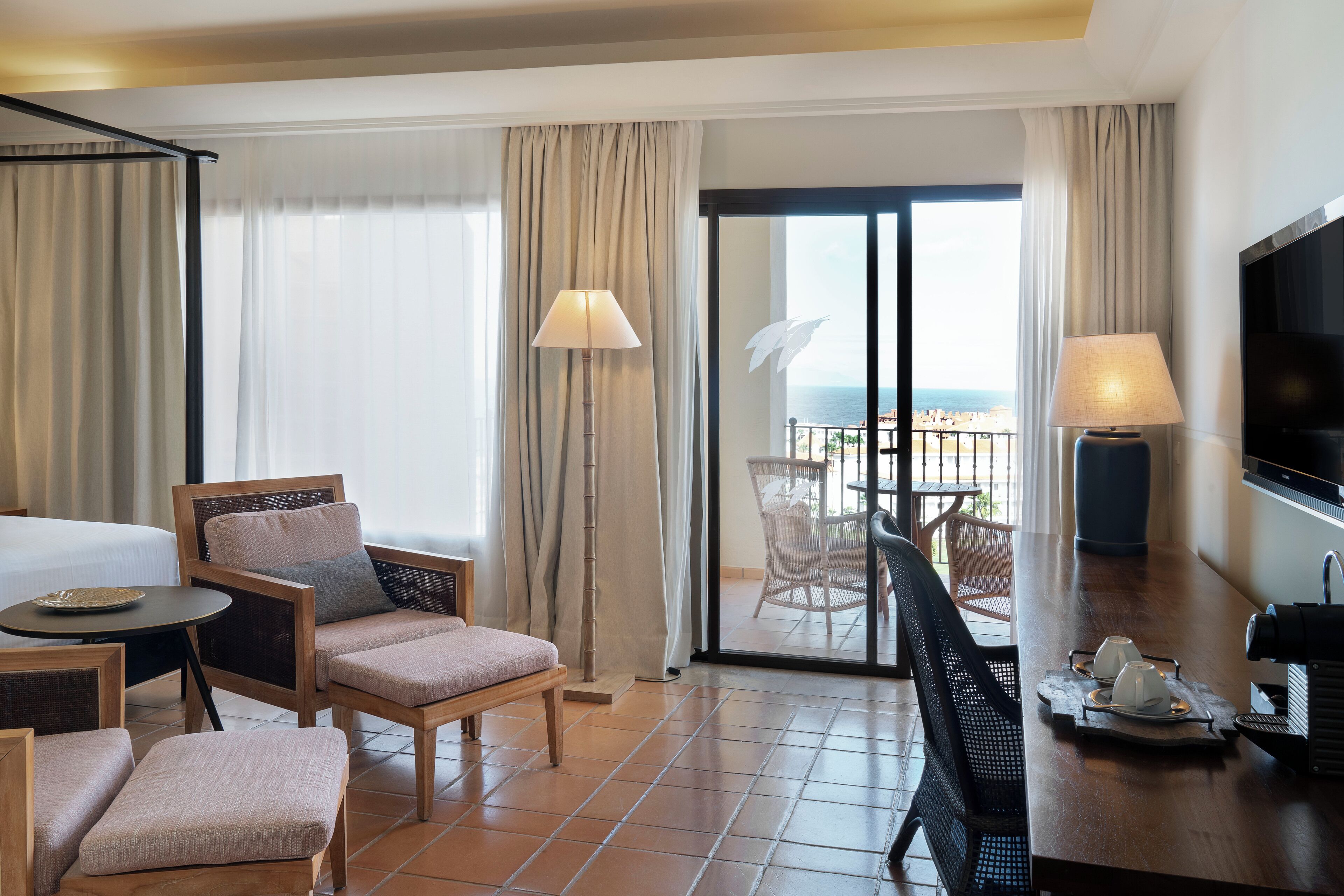Une chambre d’hôtel avec un balcon, un lit, une table à manger et un téléviseur.