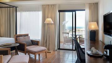 Une chambre d’hôtel avec un balcon, un lit, une table à manger et un téléviseur.
