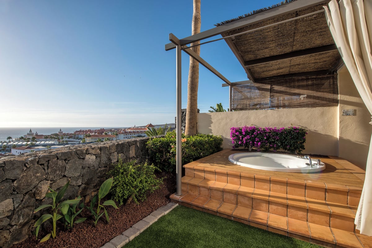 Une terrasse sur le toit avec un jacuzzi, un mur en pierre et une vue sur la ville.