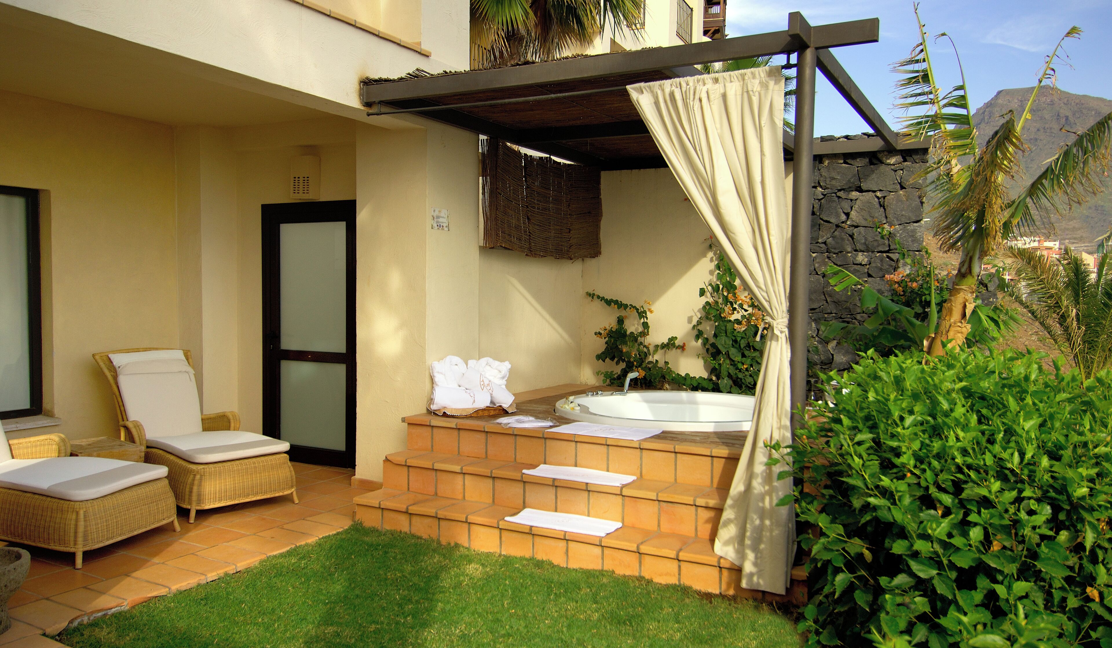 A spa area with a hot tub, lounge chairs, and a covered seating area.