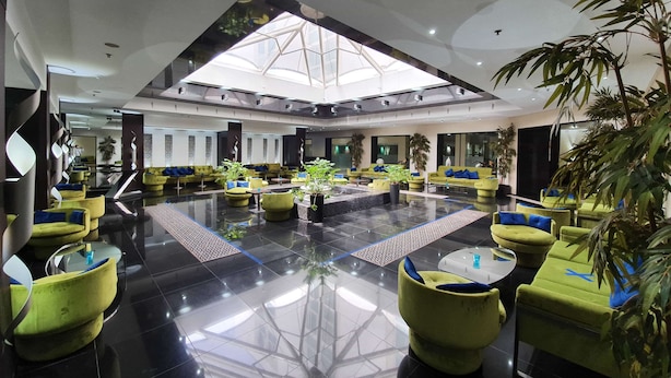 A spacious lobby with a high ceiling and skylight, featuring green sofas and potted plants. - Hotel Borj Rabat – A member of Barcelo Hotel Group (Rabat)