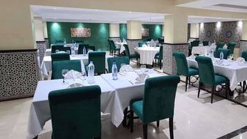 Un restaurante con varias mesas y sillas, cada conjunto con botellas de agua y vasos.