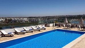 A rooftop pool with lounge chairs and tables, overlooking a marina and cityscape. - Hotel Borj Rabat – A member of Barcelo Hotel Group (Rabat)