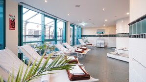 A modern spa with sun loungers, a large window, and a sink area. - Mercure Hotel Frankfurt Airport Langen (Langen)