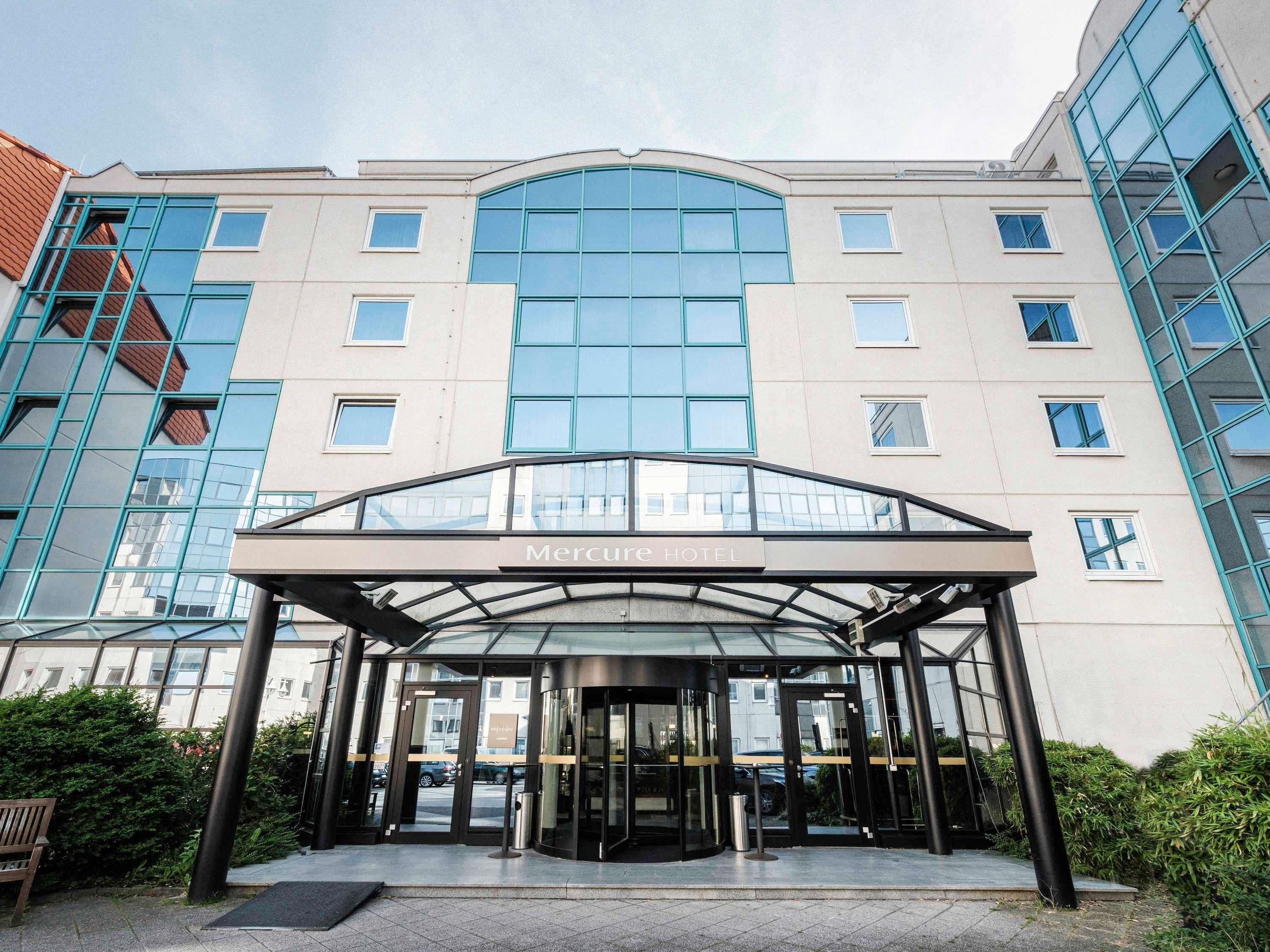 The entrance of the Mercure Hotel with a glass canopy and a modern design.