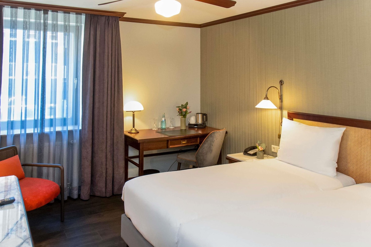 A hotel room with a bed, desk, chair, and a ceiling fan.