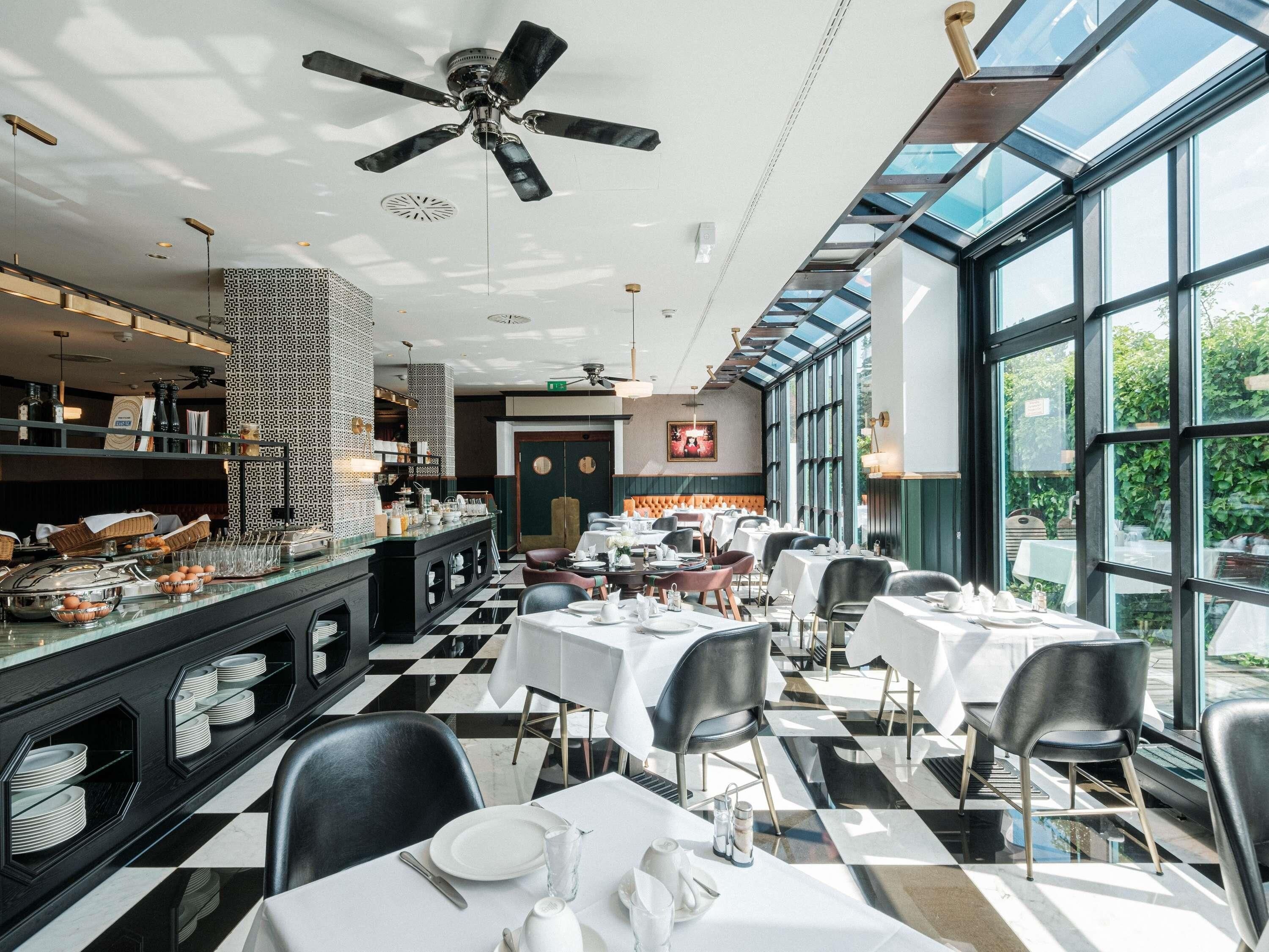 Ein Restaurant mit Schachbrettboden, schwarzen und weißen Stühlen und einem Buffet mit verschiedenen Speisen.