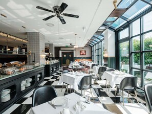 A restaurant with a checkered floor, black and white chairs, and a buffet area with various dishes. - Mercure Hotel Frankfurt Airport Langen (Langen)