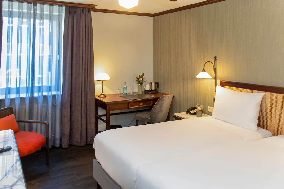 Une chambre d’hôtel équipée d’un lit, d’un bureau, d’une chaise et d’un ventilateur de plafond.