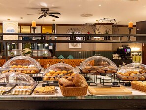 A buffet with various baked goods, including bread and pastries, covered with clear domes. - Mercure Hotel Frankfurt Airport Langen (Langen)