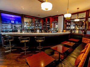 Una zona de bar con mostrador, taburetes y una recepción.