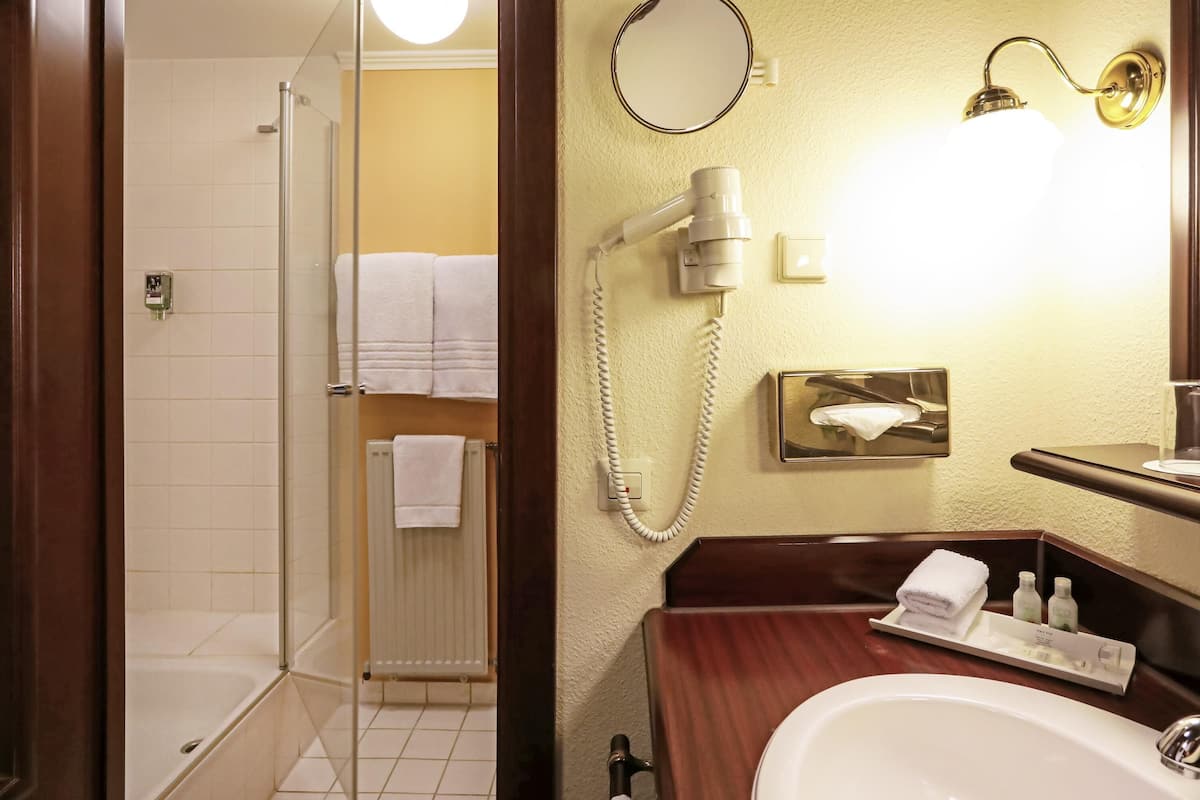 Un bagno con doccia, lavabo, specchio e asciugacapelli.