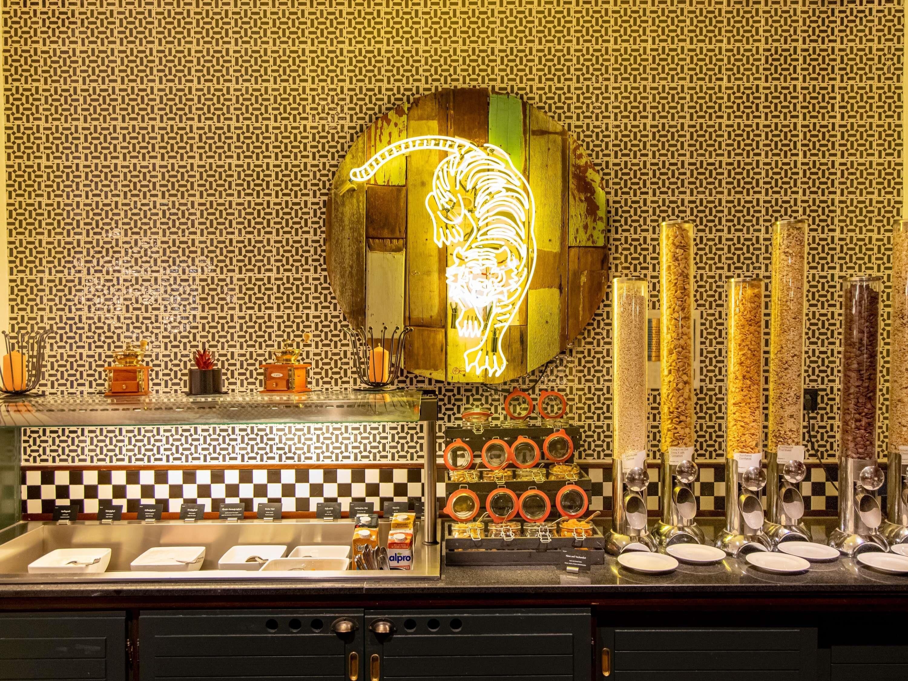 A restaurant with a neon tiger sign, checkered tile backsplash, and a buffet counter with various food items and condiments.