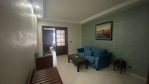 A living room with a blue sofa, a coffee table, and a painting on the wall. - Hotel Azur (Casablanca)