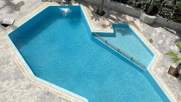 Una piscina al aire libre, sillones reclinables de piscina