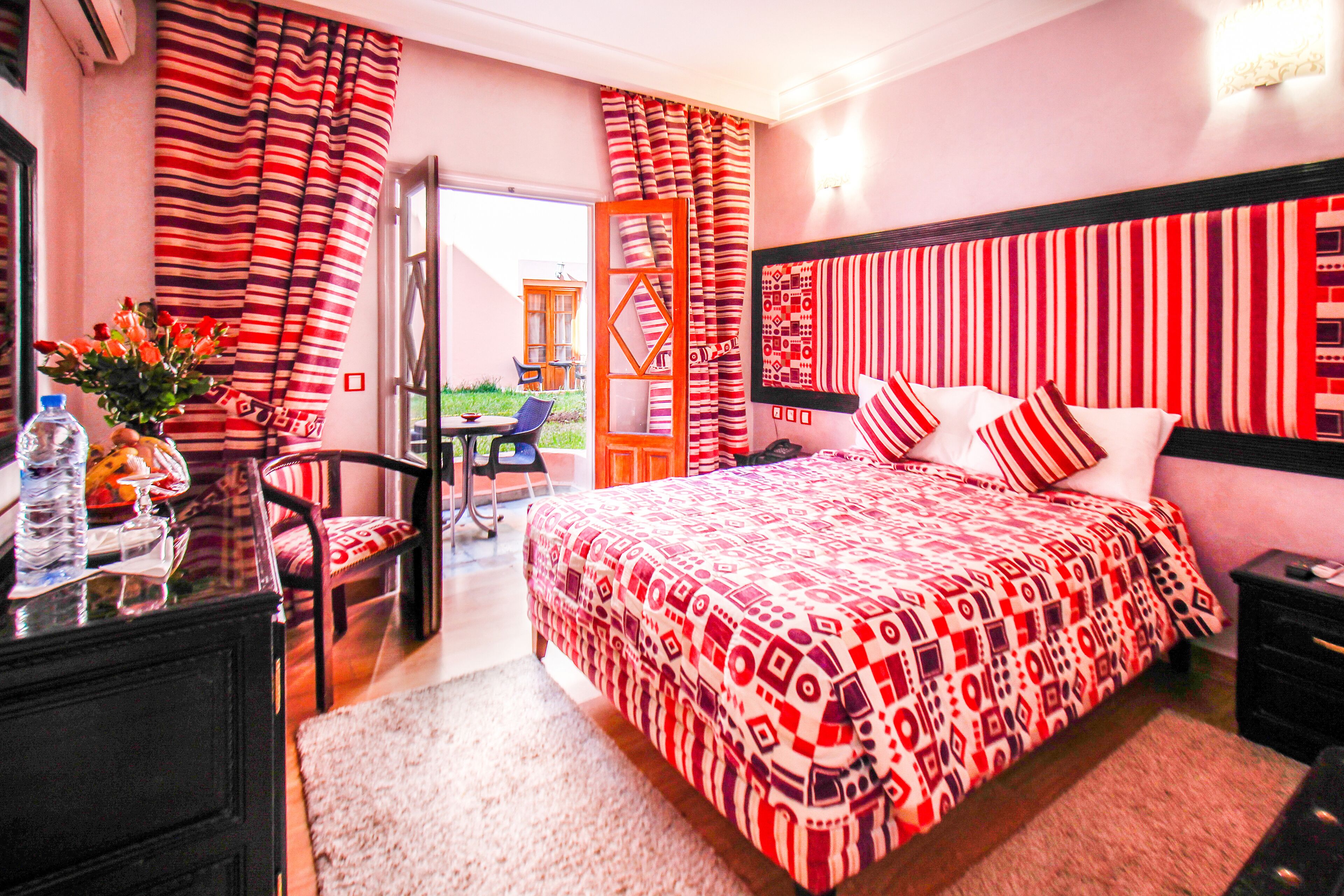 Habitación de hotel con una cama grande, un escritorio con una silla, una mesita con un florero y vistas al exterior.