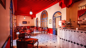 Un restaurante con sillas y mesas de madera, piso de baldosas y techo rojo.