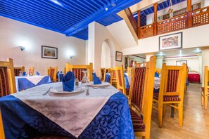 A dining area with tables set for two, wooden chairs, and a blue ceiling. - Oudaya Hotel & Spa (Marrakech)