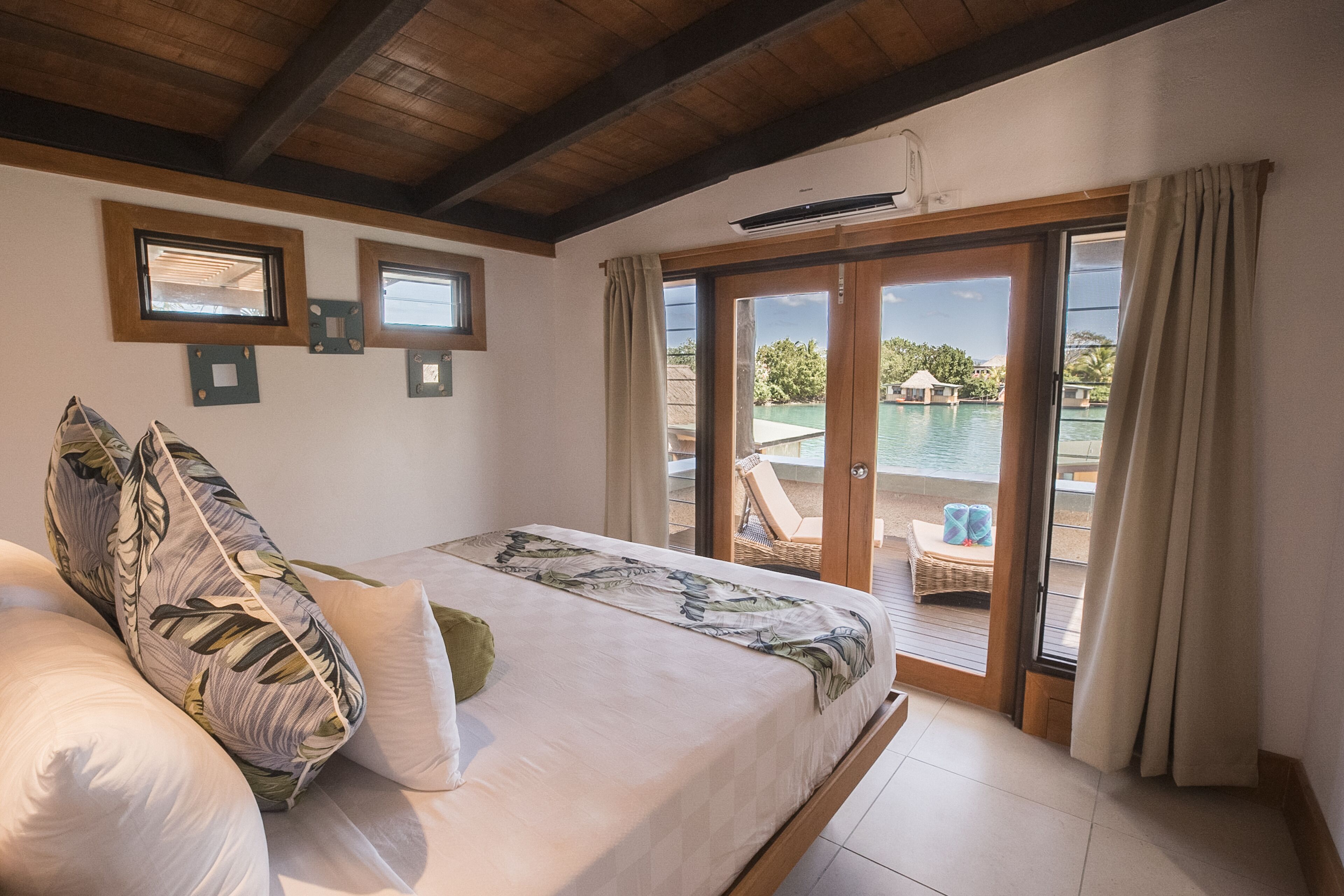 Une chambre avec un lit, une vue sur la piscine et un balcon équipé de chaises.