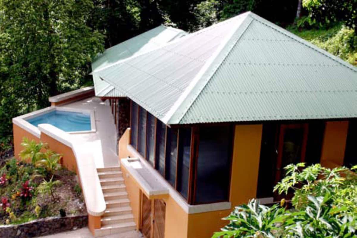 A small, single-story building with a swimming pool, surrounded by lush greenery.
