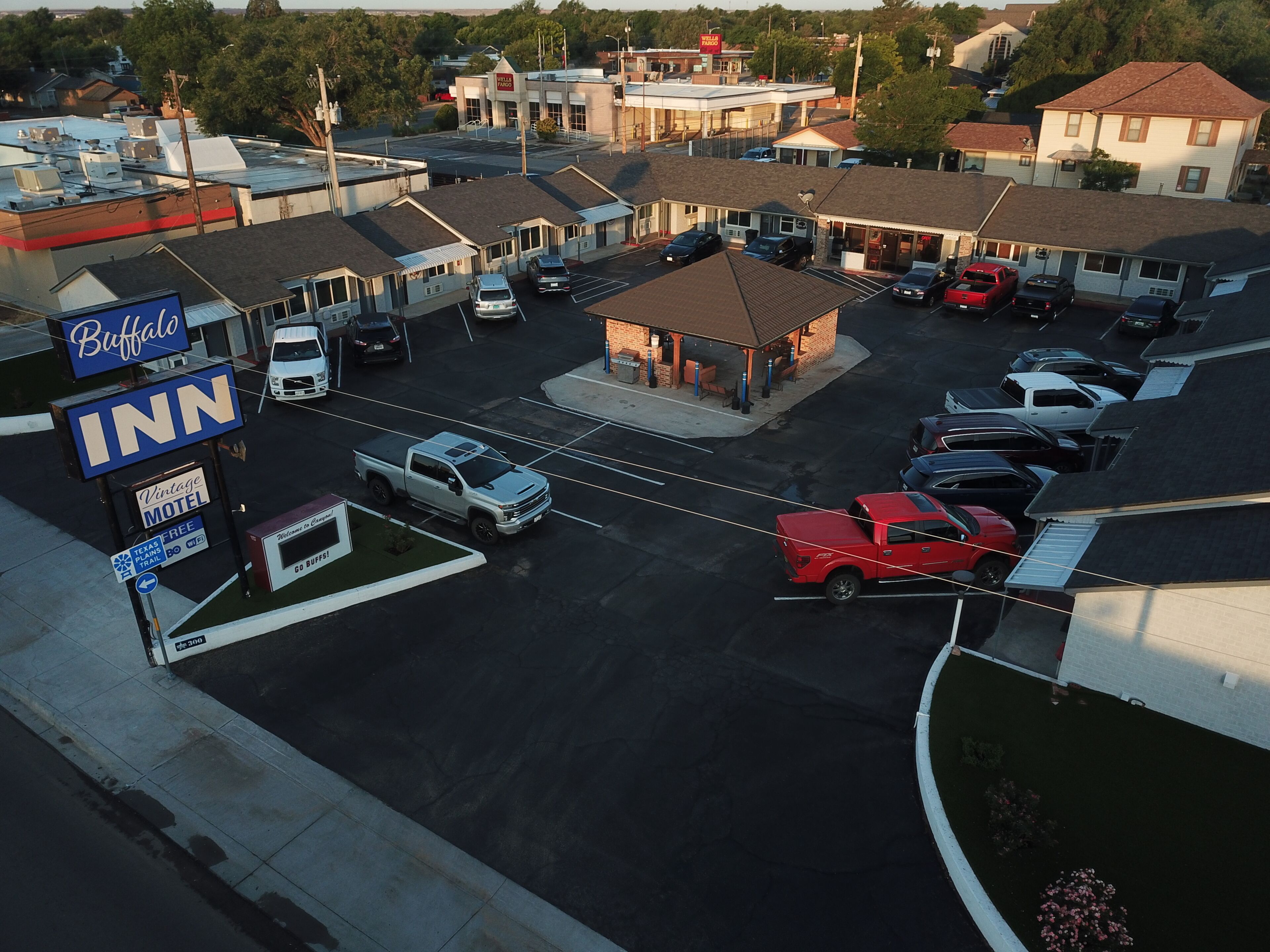 En parkeringsplads med et motel, en tankstation og en bygning med skiltning for en bank.