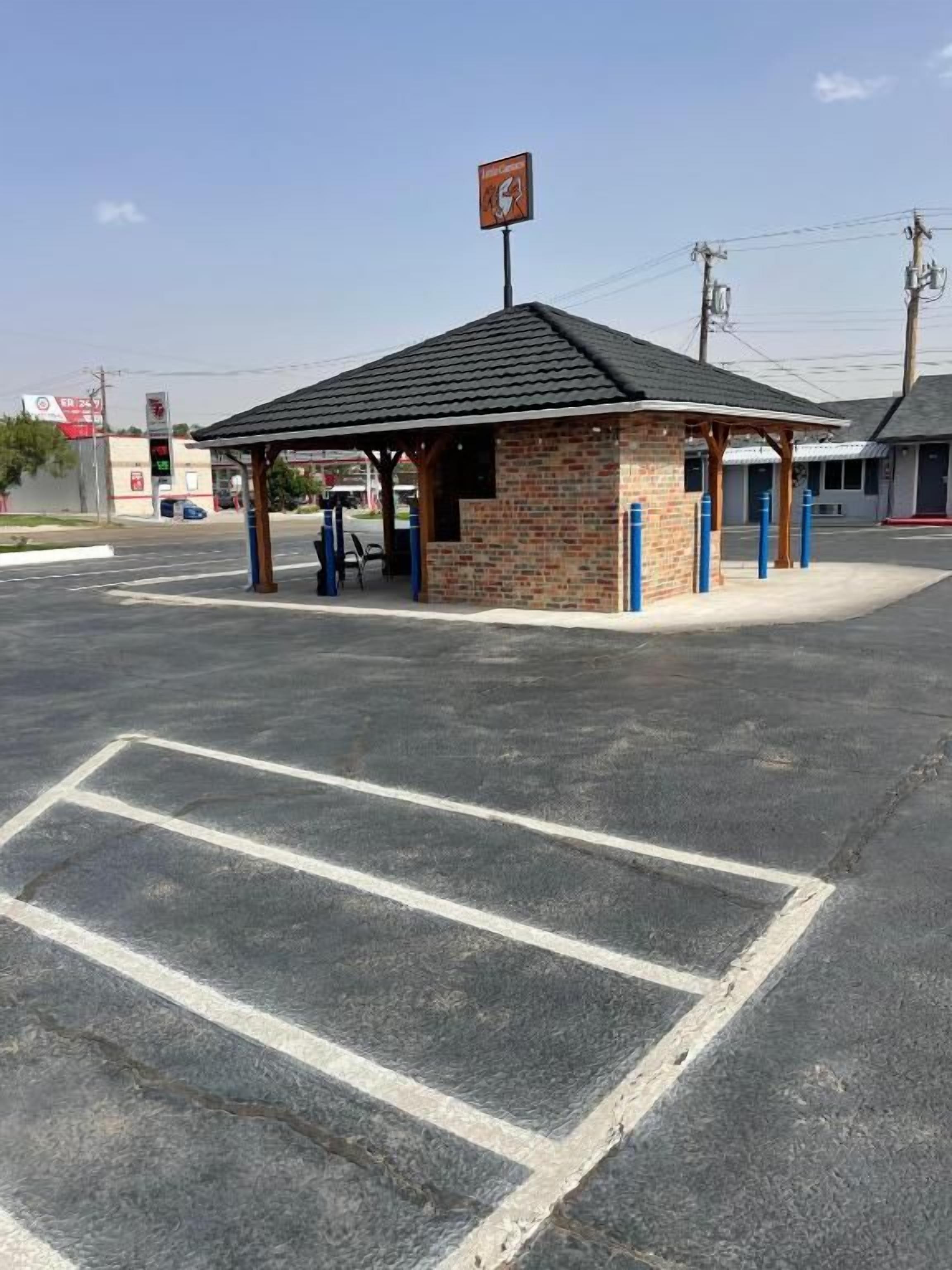 A gas station with a brick building, a covered area, and a parking lot.