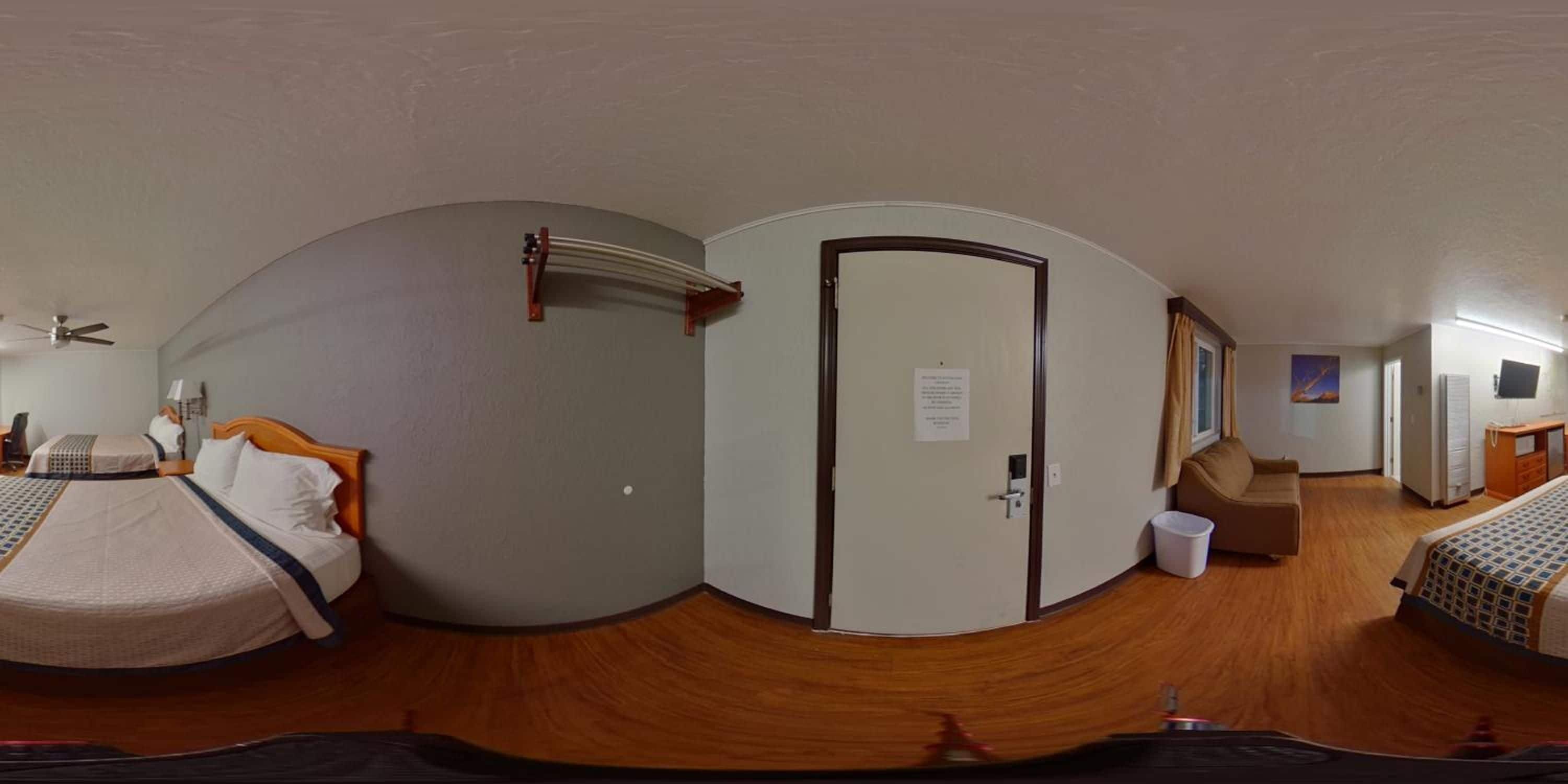 Una habitación de hotel con una cama, un escritorio, una silla, un televisor y una puerta.