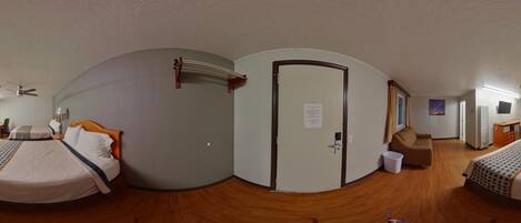 Una habitación de hotel con una cama, un escritorio, una silla, un televisor y una puerta.