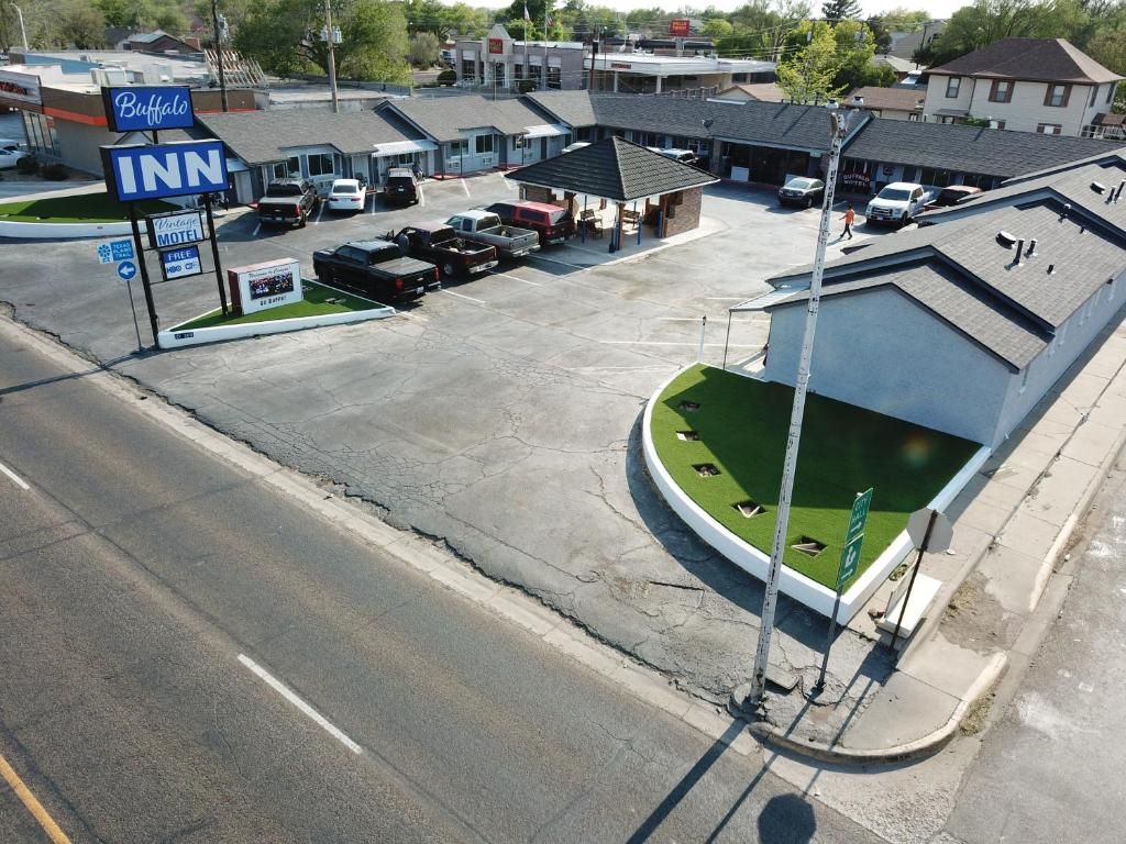 Een motel met een parkeerplaats, een klein gebouw met een schuin dak, en een bord met Buffalo Inn erop.
