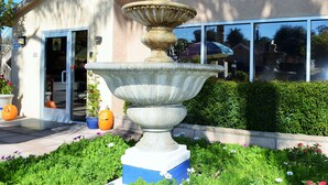 A large stone fountain in a garden with a building in the background. - Loma Linda Inn (Loma Linda)