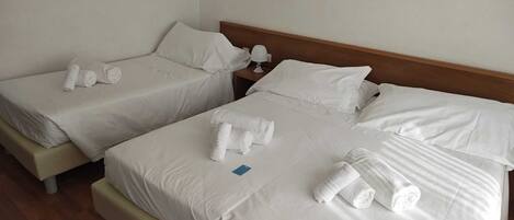 Habitación de hotel con dos camas, cada una con ropa de cama blanca y toallas enrolladas.