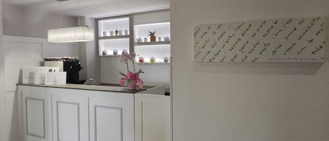A reception area with a counter, a coffee machine, and shelves with decorative items.