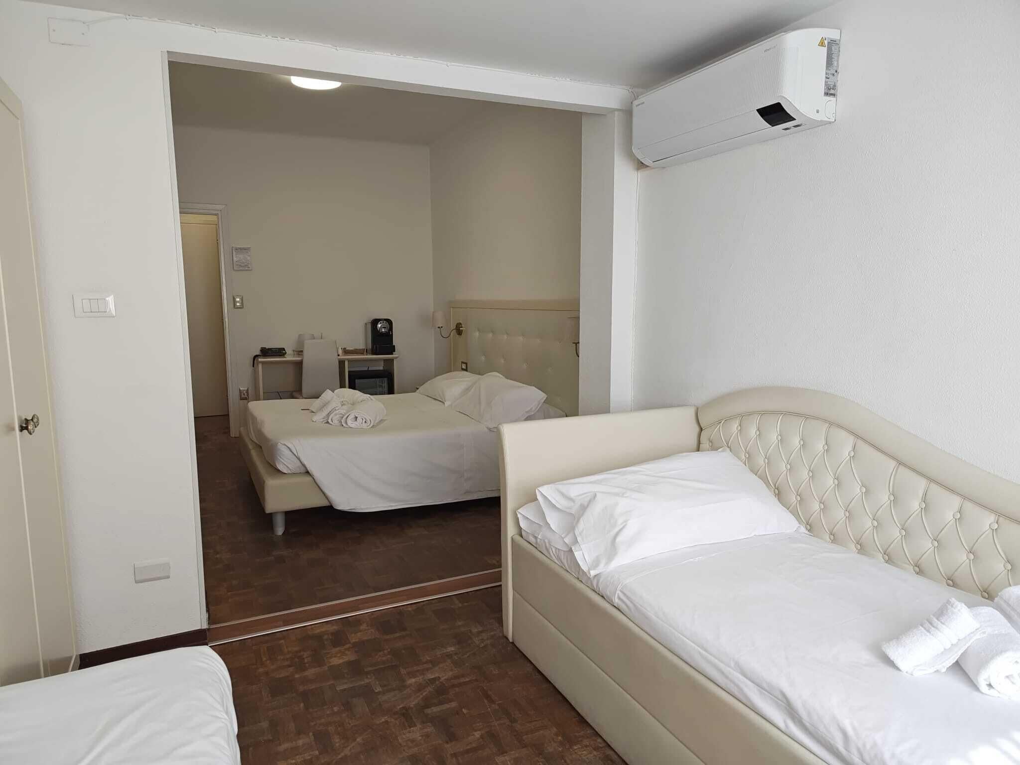 Habitación de hotel con cama, mesita de noche, silla, escritorio y aire acondicionado instalado en la pared.