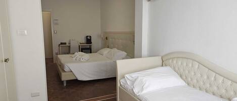 Habitación de hotel con cama, mesita de noche, silla, escritorio y aire acondicionado instalado en la pared.