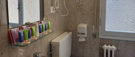 A bathroom with a sink, toilet, and a hand dryer mounted on the wall.