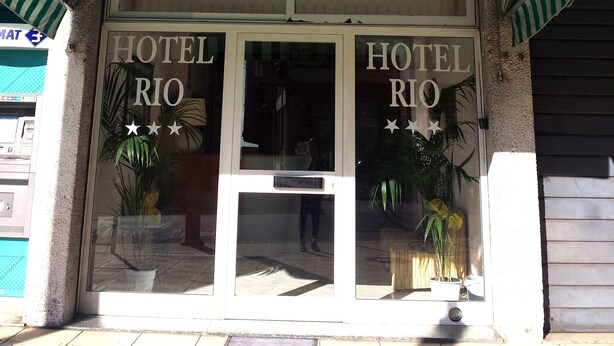 A hotel named "HOTEL RIO" with a green and white striped awning and a sign with three stars above the entrance. - Hotel Rio (Sanremo)