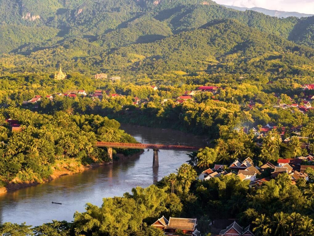 A river with a bridge, surrounded by lush greenery and residential buildings.