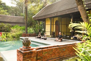 A serene outdoor yoga area with a brick wall, a pool, and lush greenery. - La Résidence Phou Vao (Luang Prabang)