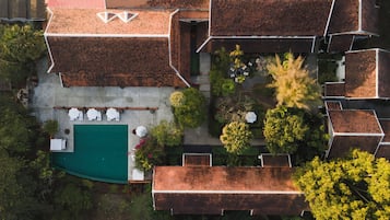 An aerial view of a residential area with a swimming pool, outdoor seating, and lush greenery.