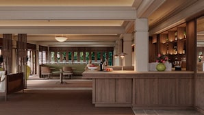 A spacious lobby with a central seating area, a bar with a green vase, and a view through a glass partition. - La Résidence Phou Vao (Luang Prabang)