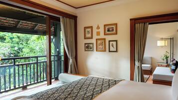 A hotel room with a large bed, a balcony with a view of greenery, and several framed pictures on the wall.
