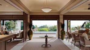A spacious room with a large dining table, comfortable seating, and a view of lush greenery outside. - La Résidence Phou Vao (Luang Prabang)