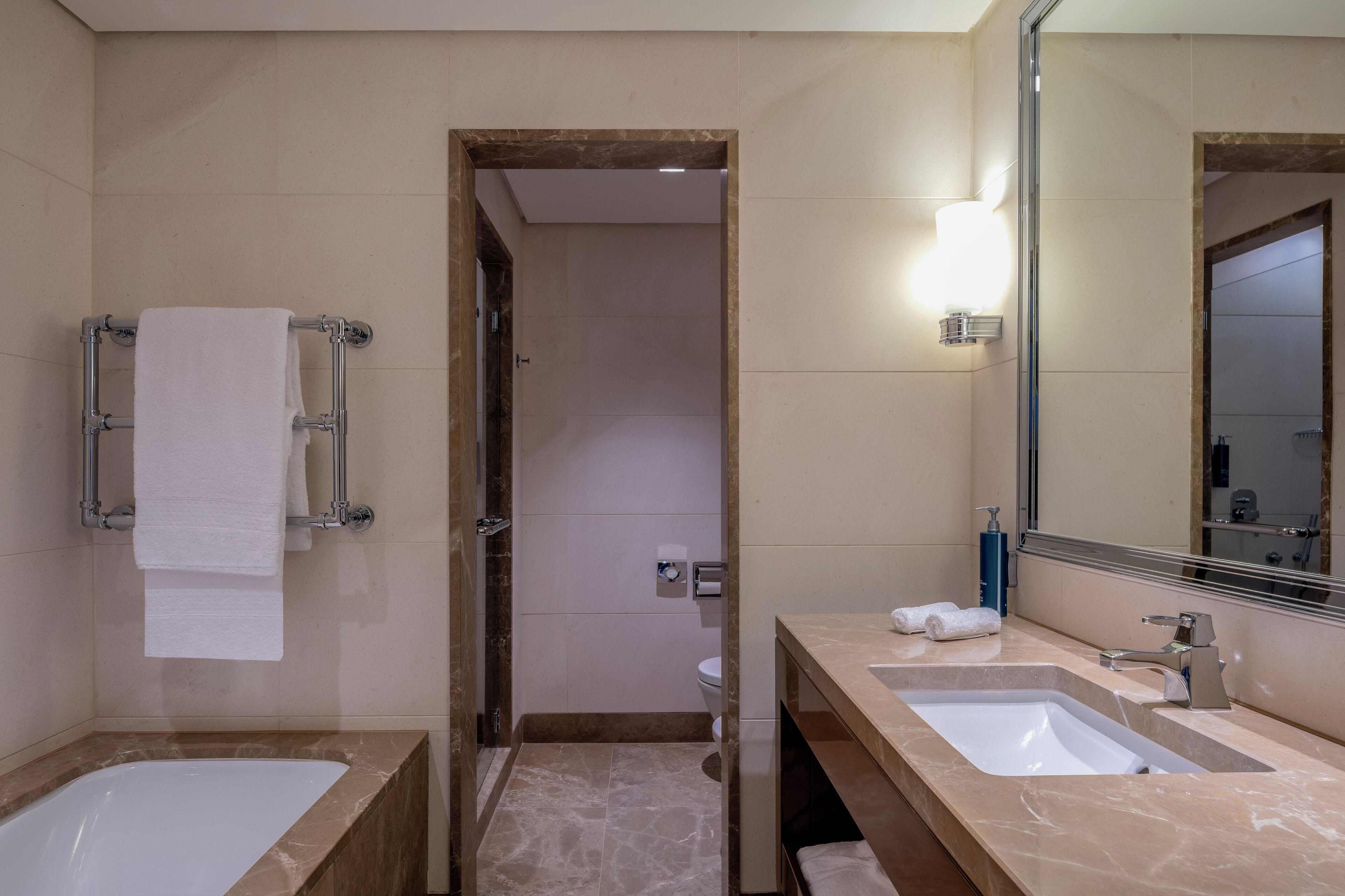 A modern bathroom with two sinks, a large mirror, and a bathtub.