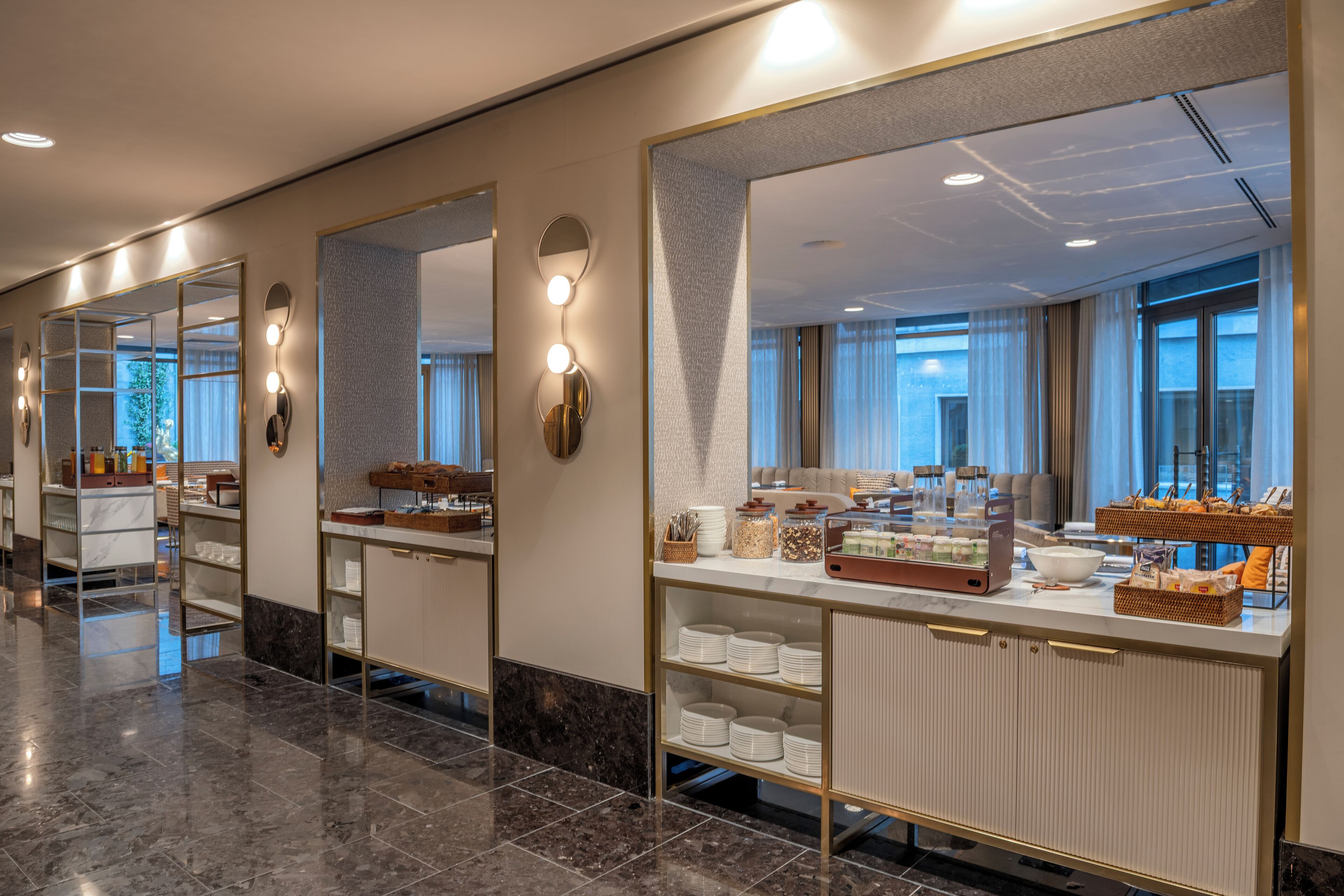 Un moderno baño de hotel con tocador, espejos y un aparador con diversos servicios.