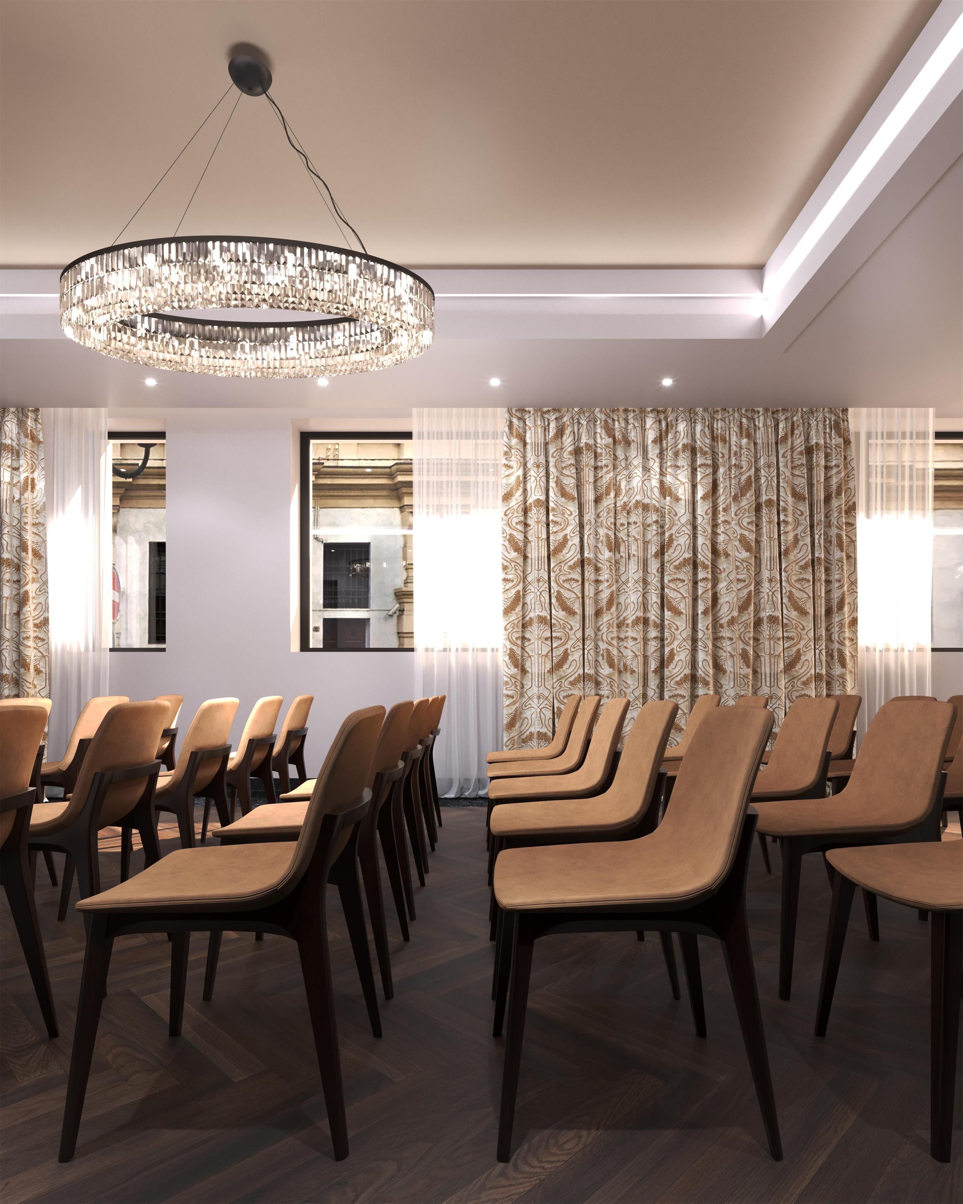 Une salle de conférence avec des rangées de chaises, un lustre et des rideaux à motifs.